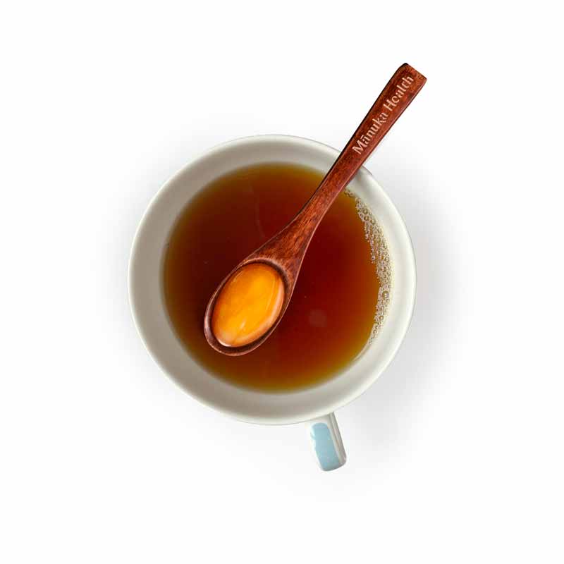 Tasse mit Tee und Holzlöffel mit Honig